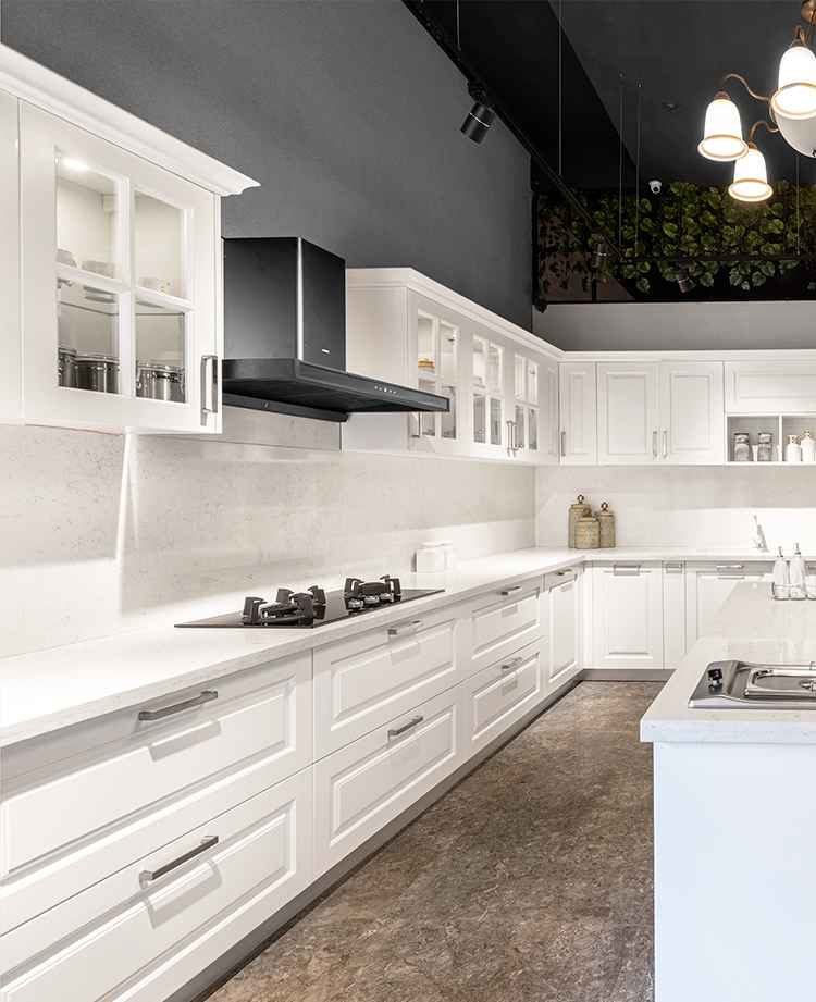 Elegant white modular kitchen with classic shaker-style cabinets, a sleek black chimney, and a spacious countertop. Features glass-paneled upper cabinets, under-cabinet lighting, and a luxurious contemporary design.