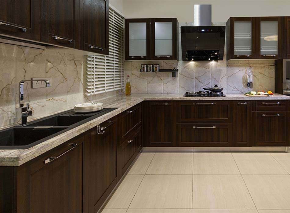 Alea 17 Luxurious modular kitchen by alea, featuring rich dark wood cabinetry, marble countertops, and a sleek black sink. The elegant backsplash, modern chimney, and under-cabinet lighting enhance the contemporary yet classic design, creating a perfect blend of style and functionality.
