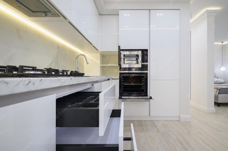 Modular kitchen cabinets: the ultimate guide 1 Sleek white modular kitchen by alea modular featuring handleless cabinets, soft-close drawers, built-in oven and microwave, and a marble-finish countertop. High-end modern kitchen design with space-efficient storage solutions and premium finishes.