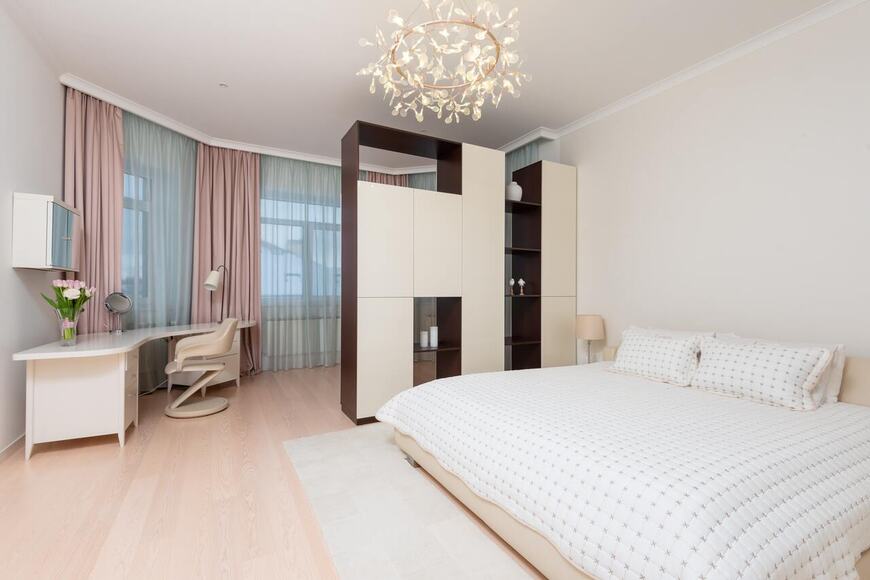 Elegant modular wardrobe by alea modular kitchen, featuring a stylish partition design with open shelves and closed storage for a modern bedroom. The space is well-lit with a luxurious chandelier, cozy bed, and a functional study desk, offering a perfect blend of aesthetics and functionality.