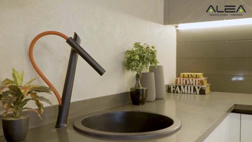 How do i redesign my kitchen layout? 1 Stylish modern kitchen sink area by alea modular kitchen, featuring a sleek black countertop, unique designer faucet, and decorative elements that enhance the elegant redesign kitchen layout